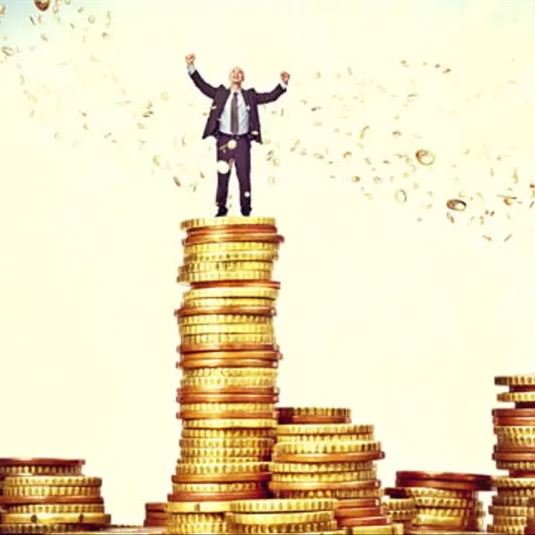Rich man standing on a pile of oversized coins