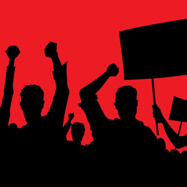 Silhouette of a crowd with placards and fists aloft