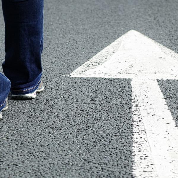 Man walking on road with arrow
